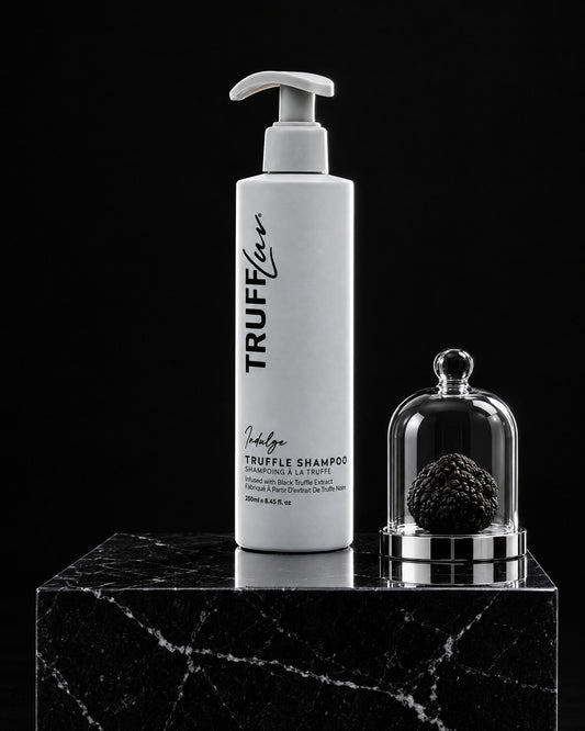 TRUFFLuv Truffle Shampoo Indulge auf schwarzem Marmorsockel neben schwarzer Trüffel unter einer Glasglocke