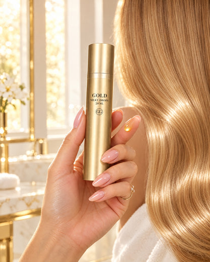 Hand hält GOLD Silky Drops mit einem Tropfen Serum vor langem, glänzendem, blondem Haar