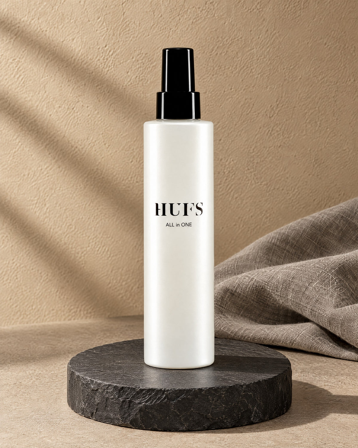 HUFS All in One Leave-in Spray 200 ml in perlweißer Sprühflasche auf dunklem Schiefer-Sockel
