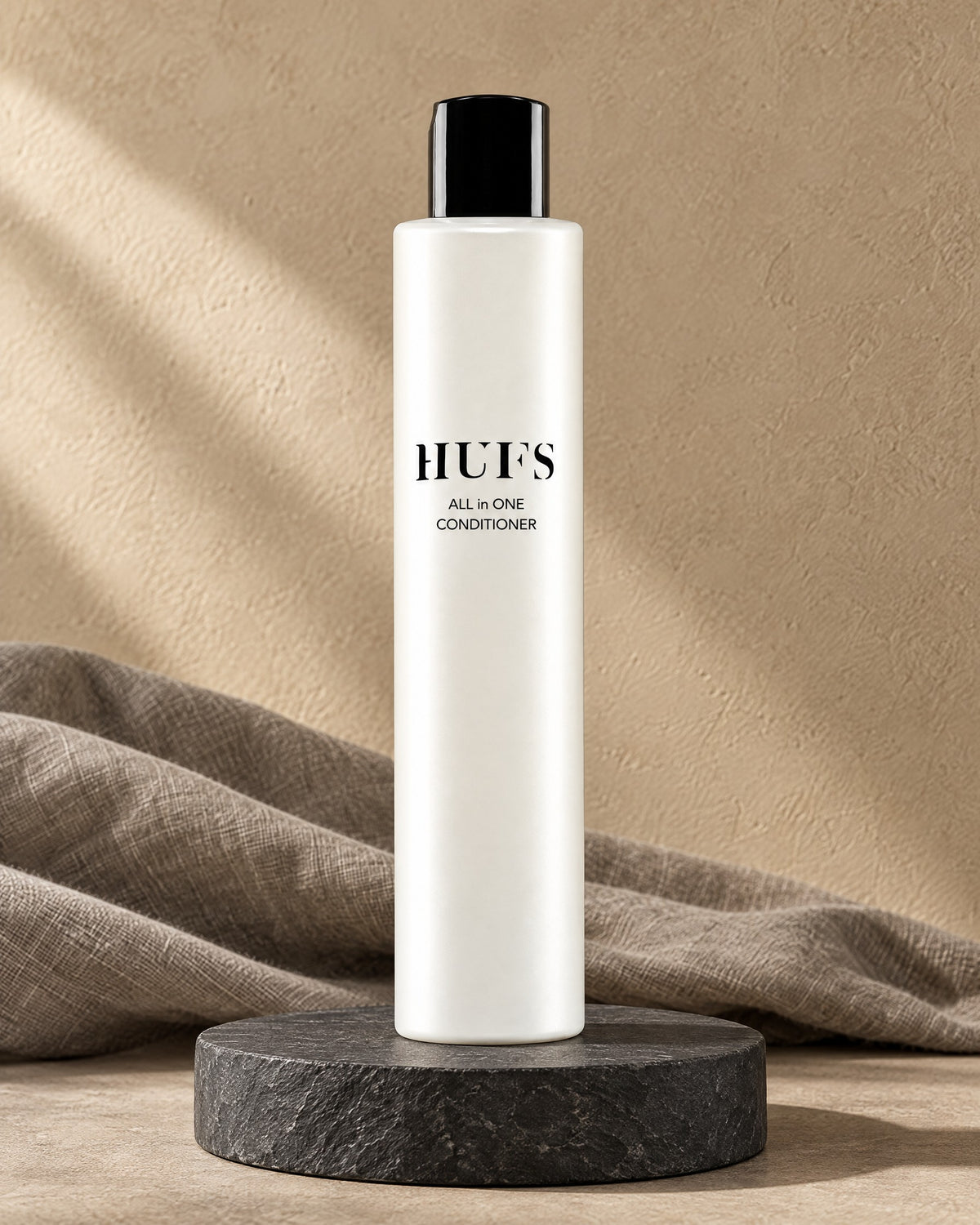 HUFS All in One Conditioner für trockenes Haar in perlweißer Flasche auf dunklem Schiefer-Sockel