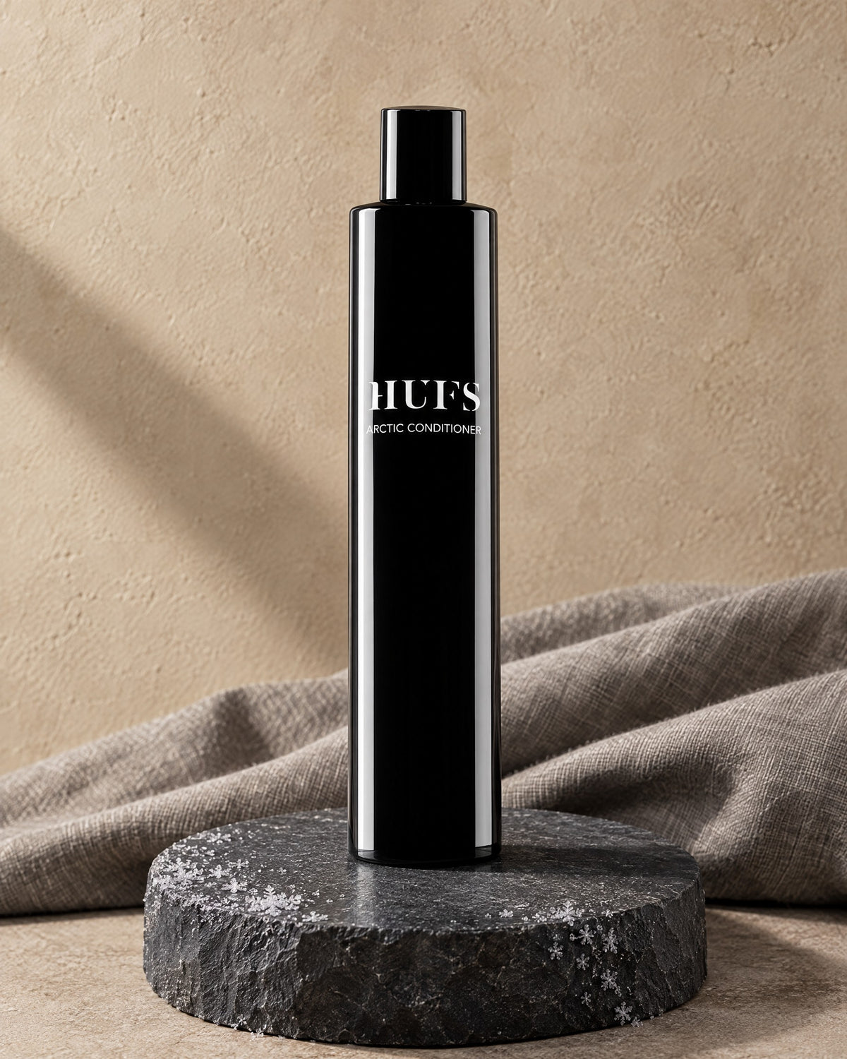 HUFS Arctic Anti-Schuppen Conditioner in glänzend schwarzer Flasche auf Schiefer-Sockel mit Raureif