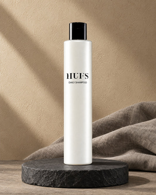HUFS Daily Shampoo für feines Haar in perlweißer Flasche mit schwarzem Deckel auf dunklem Schiefer