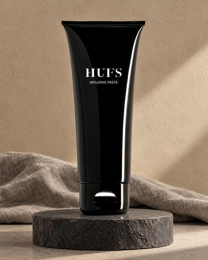 HUFS Molding Paste 100 ml Stylingpaste in glänzend schwarzer Tube auf dunklem Schiefer-Sockel