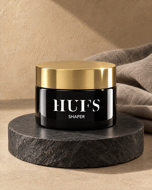 HUFS Shaper Wax 85 ml im schwarzen Tiegel mit goldenem Deckel auf dunklem Schiefer-Sockel