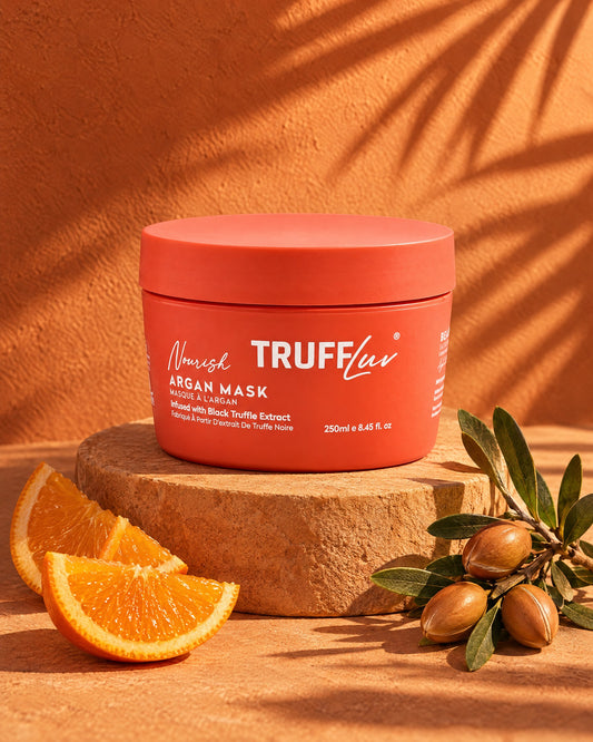 TRUFFLuv Argan Mask im korallfarbenen Tiegel auf Sandstein mit Orangenscheiben und Arganzweig