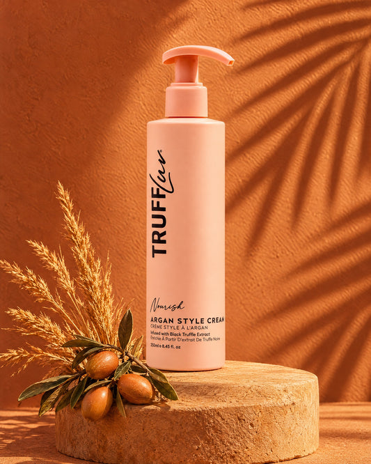 TRUFFLuv Argan Style Cream in apricotfarbener Pumpflasche auf Sandstein vor Terrakotta-Wand mit Arganzweig