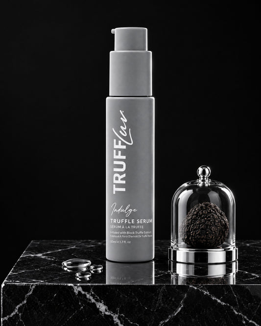 TRUFFLuv Truffle Serum Indulge auf schwarzem Marmorsockel neben schwarzer Trüffel unter einer Glasglocke und Serumtropfen